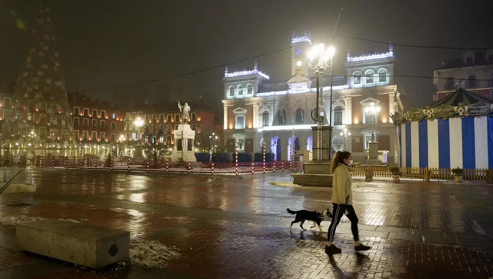 Una mujer pasea a su perro en la Plaza Mayor de Valladolid fuera del toque de queda