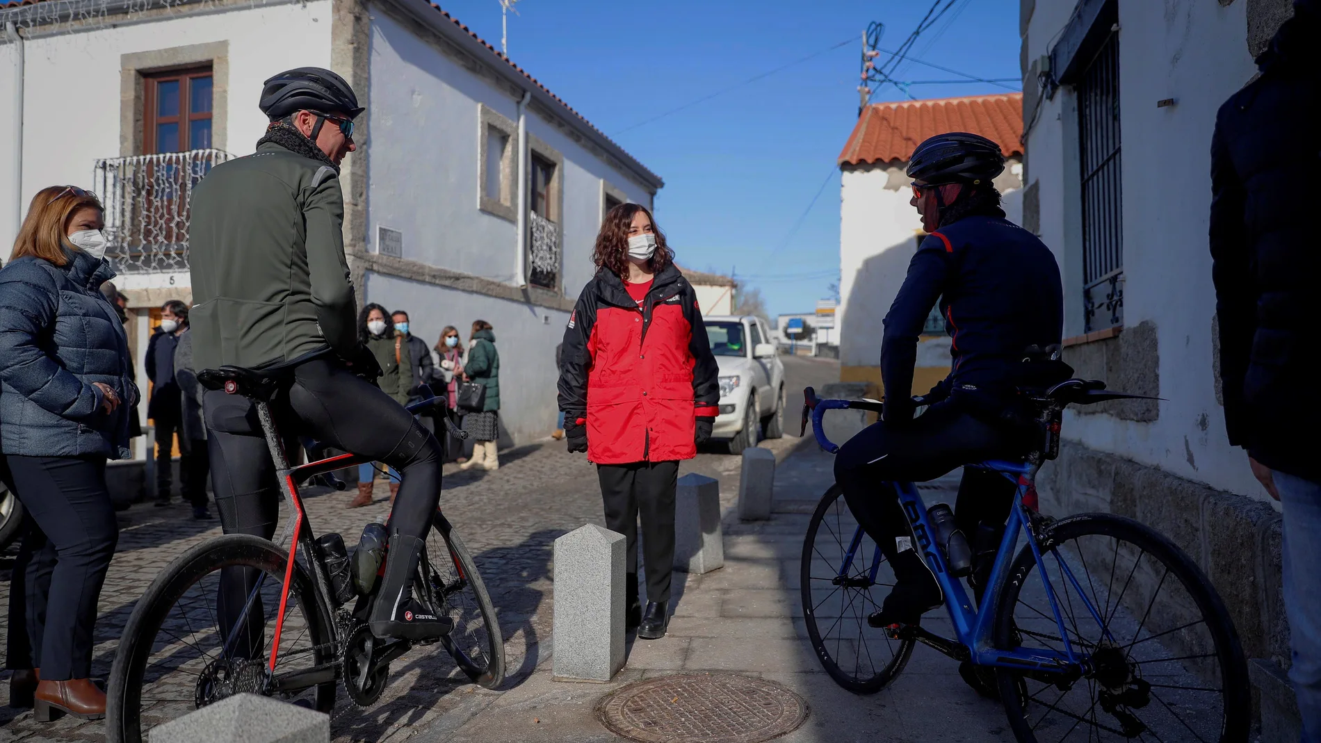 La presidenta de la Comunidad de Madrid, Isabel Díaz Ayuso, habla con dos ciclistas en su visita este domingo a la localidad de Colmenar de Arroyo para conocer de primera mano los efectos de la borrasca Filomena en el sector primario de la región