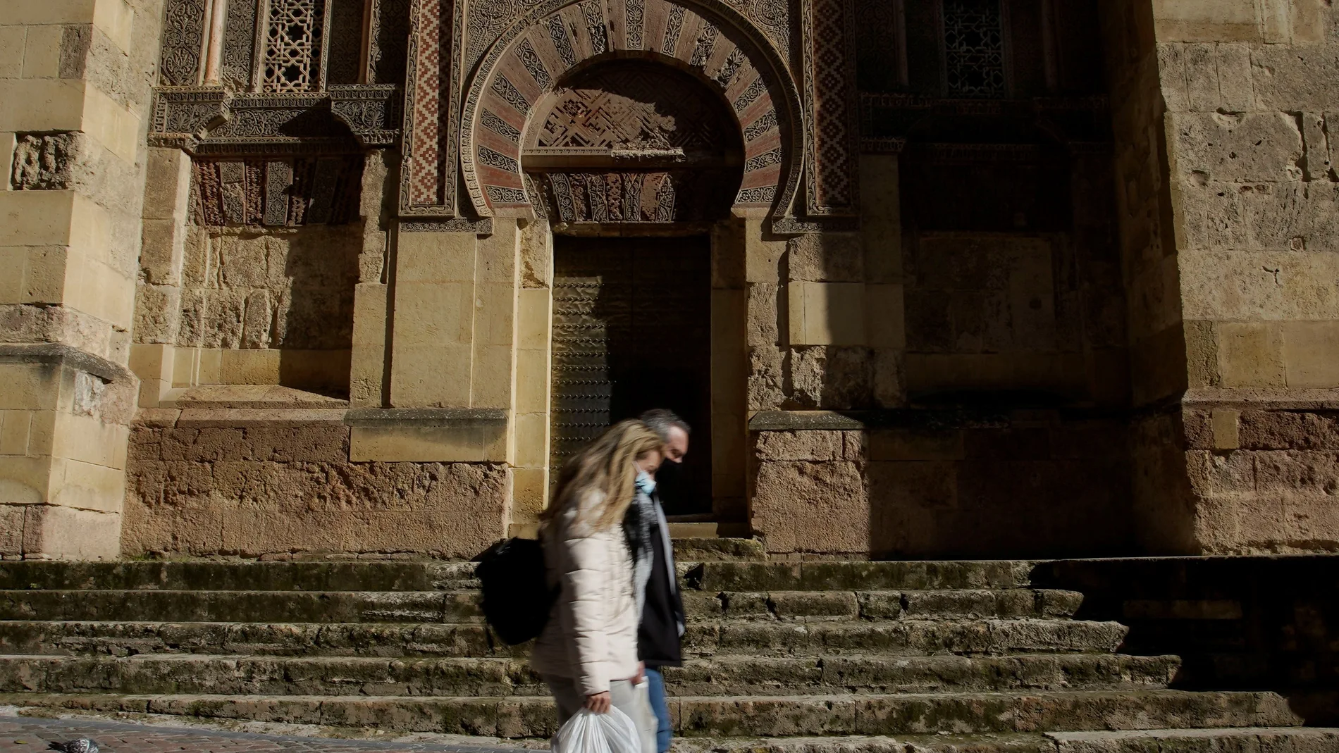 DOs personas caminan junto a la Mezquita-Catedral de Córdoba
