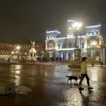Una mujer pasea a su perro en la Plaza Mayor de Valladolid durante el primer día del toque de queda a las ocho