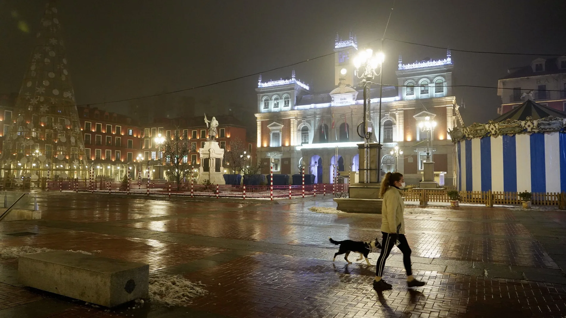 Una mujer pasea a su perro en la Plaza Mayor de Valladolid durante el primer día del toque de queda a las ocho