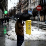 Una persona camina protegida por la capital el mismo día de la llegada del temporal ‘Gaetán’, en Madrid