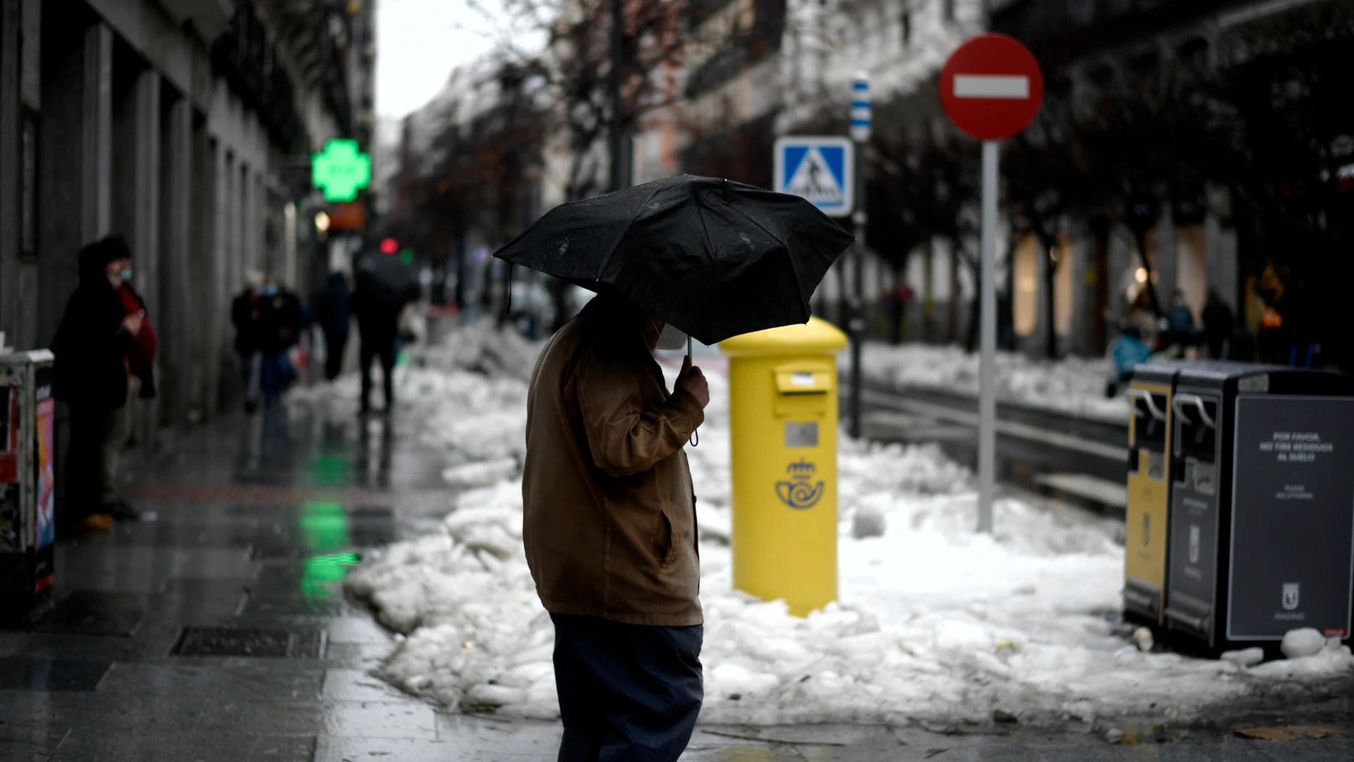 Una persona camina protegida por la capital el mismo día de la llegada del temporal ‘Gaetán’, en Madrid