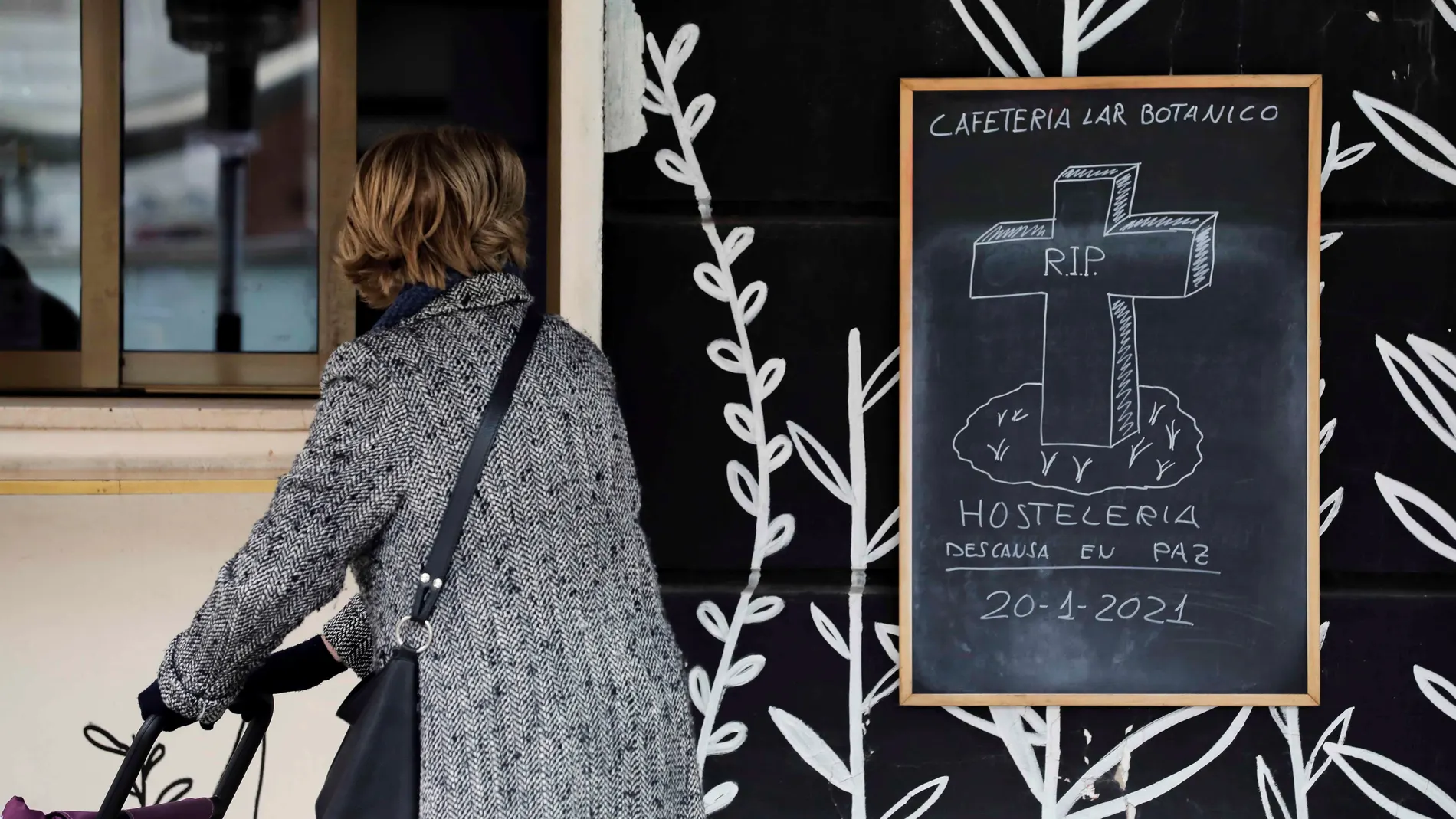 GRAFCVA1223. VALENCIA, 20/01/2021.-Una mujer observa un cartel colocado en una cafetería de Valencia, cuando la hostelería y la restauración de la Comunitat Valenciana se preparan para su cierre total desde el jueves y durante dos semanas, la principal de las nuevas medidas adoptadas por el Gobierno de Ximo Puig para hacer frente a la covid-19. EFE/Ana Escobar