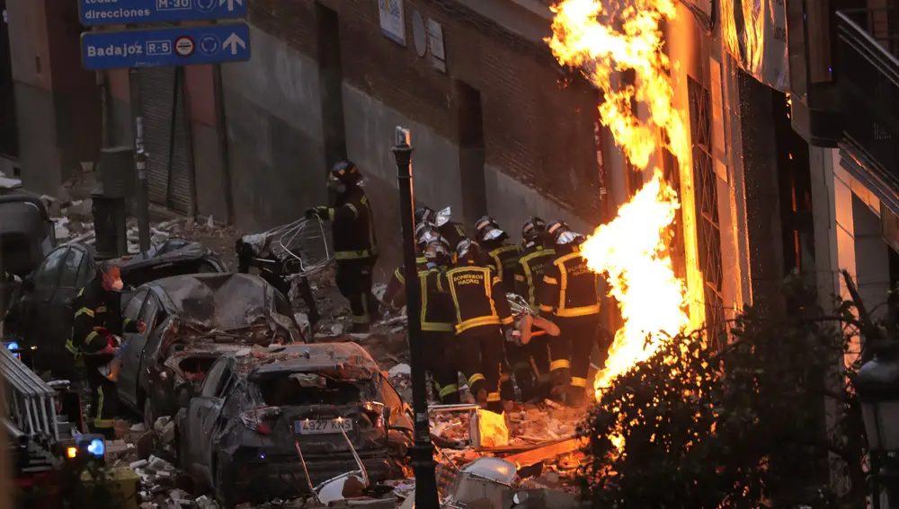 Fire-fighters carry a dead body next to a damaged building at Toledo Street following an explosion in downtown Madrid, Spain, Wednesday, Jan. 20, 2021. A powerful explosion apparently caused by a gas leak has ripped the facade off a residential building in central Madrid. (AP Photo/Manu Fernandez)