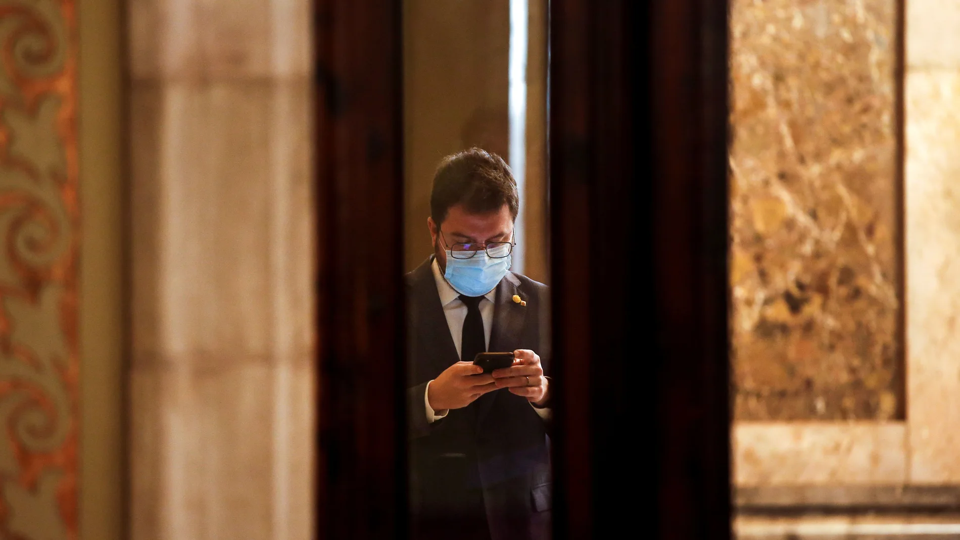 GRAFCAT7215. BARCELONA (ESPAÑA), 20/01/2021.- El vicepresidente del Govern con funciones de Presidente, Pere Aragonés, consulta su móvil en los pasillos del Parlament antes de que arranque la reunión de la diputación permanente con el debate sobre las solicitudes de comparecencia del conseller de Empresa y Conocimiento, Ramon Tremosa, y del conseller de Educación, Josep Bargalló. EFE/ Quique García