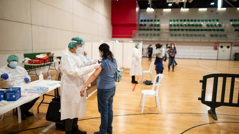 Empleados sanitarios vacunan a una compañera de profesión contra el Covid-19 en el pabellón Cabezo Baeza de Cartagena, en Murcia