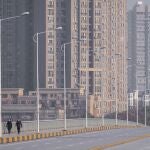 FILE - In this Jan. 28, 2020, file photo, people wearing face masks walk down a deserted street in Wuhan in central China's Hubei Province. (AP Photo/Arek Rataj, File)