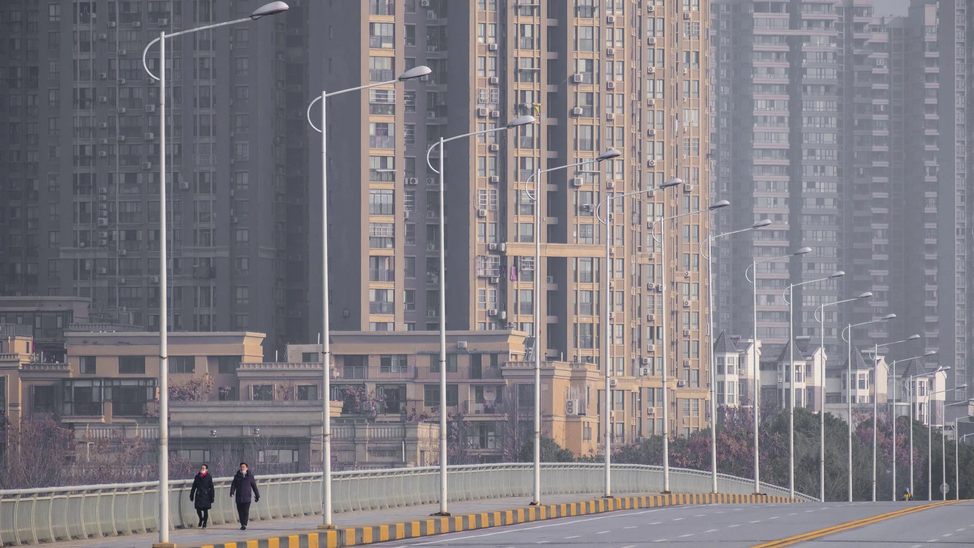 FILE - In this Jan. 28, 2020, file photo, people wearing face masks walk down a deserted street in Wuhan in central China's Hubei Province. (AP Photo/Arek Rataj, File)