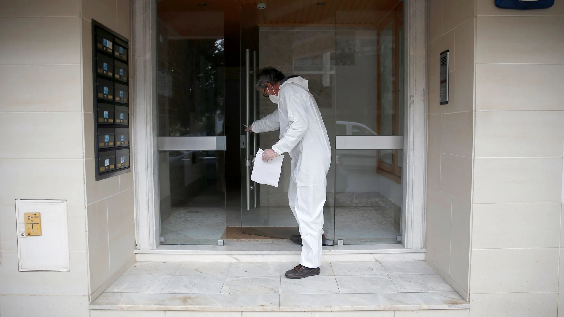 Un trabajador con equipo protector acude a una vivienda de unos votantes en cuarentena para recoger sus votos en plena oleada de casos de coronavirus