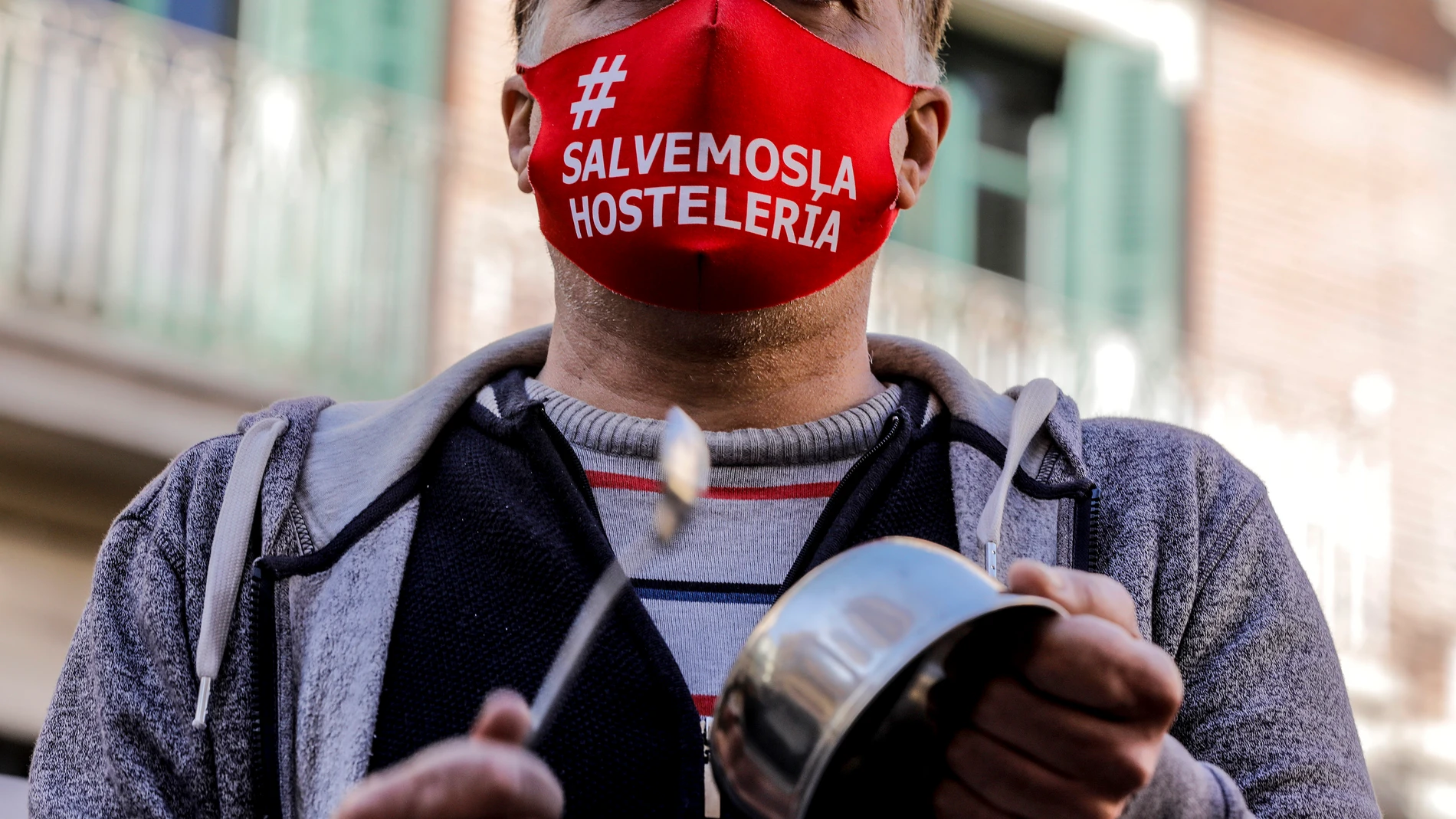 Un hombre con una mascarilla en la que se lee: `Salvemos la hostelería´ durante la cacerolada promovida por La Coordinadora Empresarial del Ocio y la Hostelería contra el cierre de la hostelería en la Comunidad Valenciana, durante la pandemia