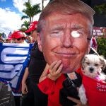 Una persona sostiene una máscara con la imagen de Donald Trump mientras esperaba su llegada a Florida