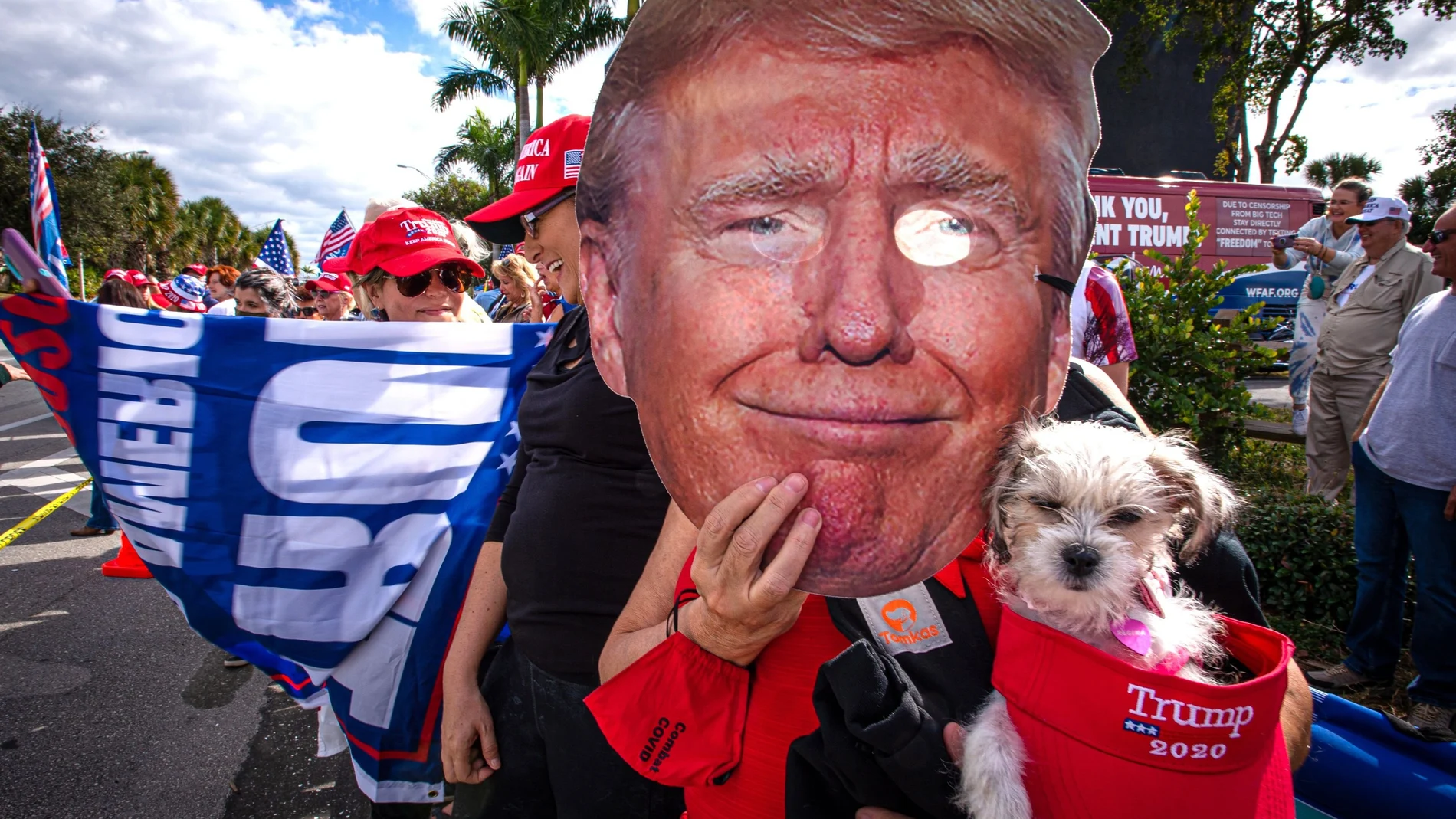 Una persona sostiene una máscara con la imagen de Donald Trump mientras esperaba su llegada a Florida