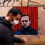 Un hombre con mascarilla pasa delante de un póster de Alexei Navalni en Roma