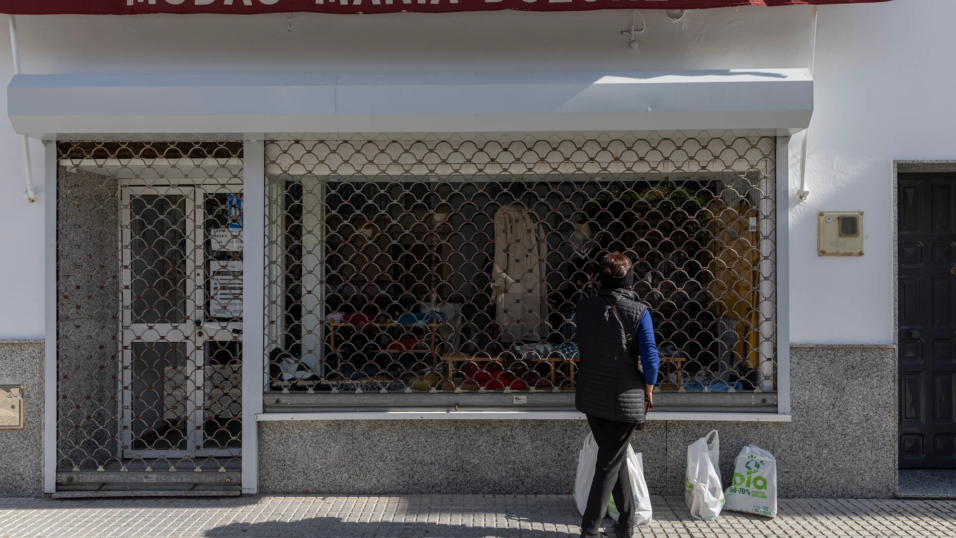 Una mujer observa el escaparate de una tienda de ropa en La Algaba (Sevilla). María José López / Europa Press