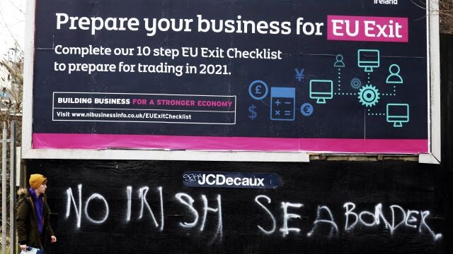 Un hombre pasa junto a un grafiti que dice "Sin frontera con el mar de Irlanda" al sur de Belfast, Irlanda del Norte