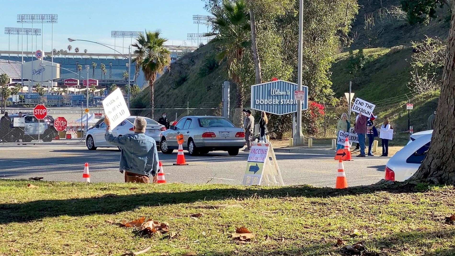 Manifestantes sosteniendo pancartas cerca de la entrada del centro de vacunación en el Estadio de los Dodgers en Los Ángeles. Fuente: @DAVEEDKAPOOR
