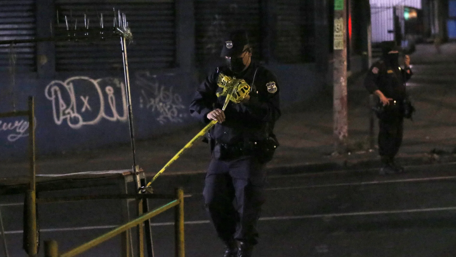 AME2370. SAN SALVADOR (EL SALVADOR), 31/01/2021.- Un policía custodia hoy la escena donde fueron heridos simpatizantes del partido de izquierda Frente Farabundo Martí para la Liberación Nacional en San Salvador (El Salvador). Al menos dos personas murieron y otras cinco resultaron heridas en El Salvador este domingo por la noche víctimas de un ataque armado contra un grupo de simpatizantes del partido opositor Frente Farabundo Martí para la Liberación Nacional (FMLN, izquierda), informó la Fiscalía General de la República (FGR). EFE/Rodrigo Sura