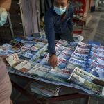 Un vendedor de periódicos señala la portada de uno de ellos hoy en Yangon, Myanmar