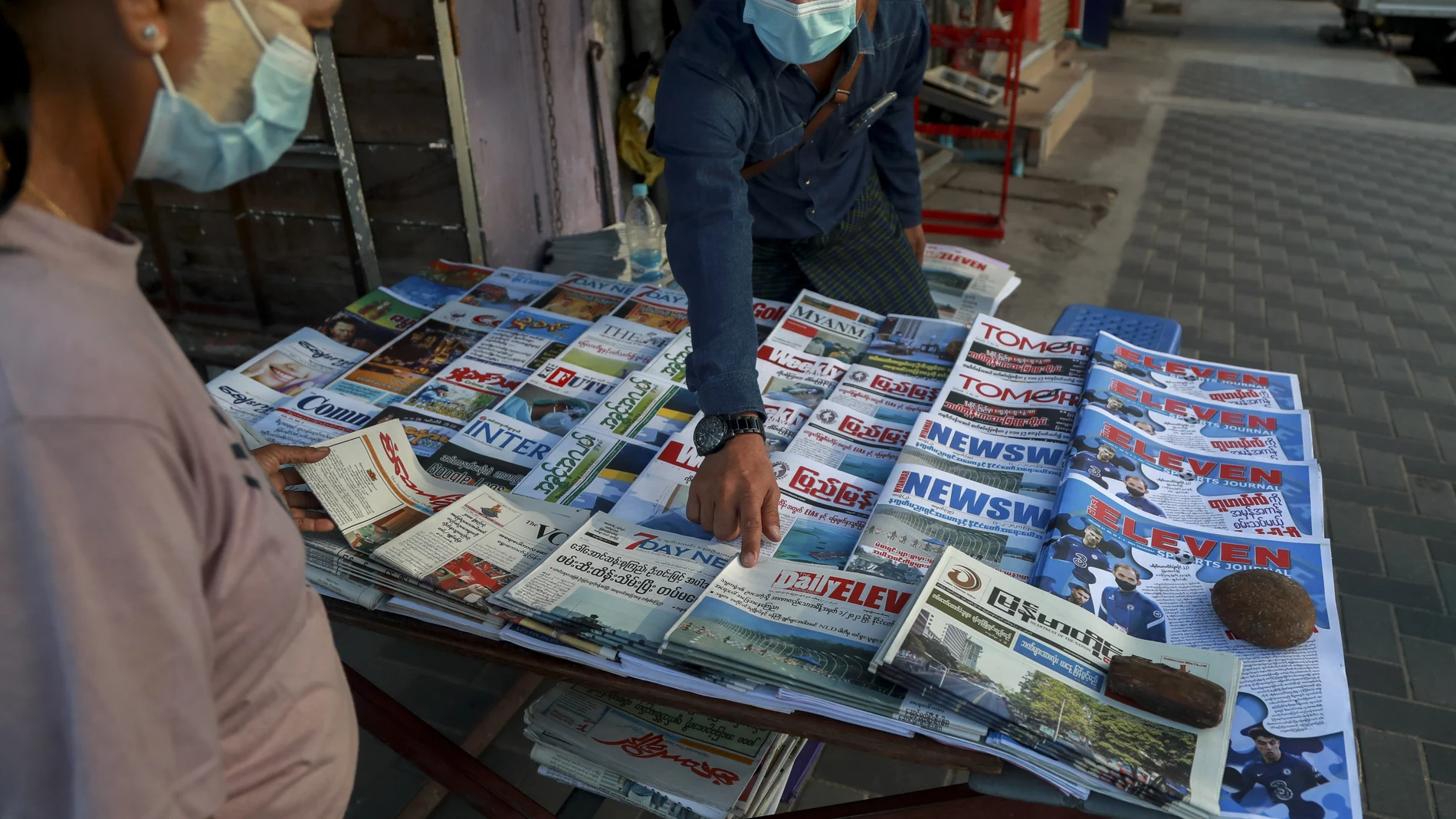 Un vendedor de periódicos señala la portada de uno de ellos hoy en Yangon, Myanmar