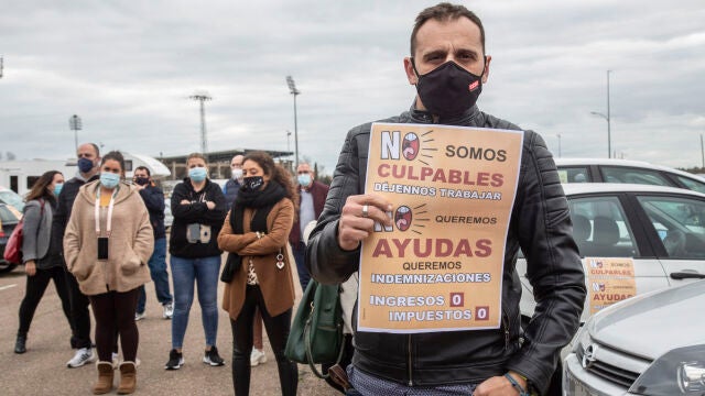 Un hombre con un cártel en el que se lee: `No somos culpables, déjenos trabajar´ durante una caravana reivindicativa de hosteleros y comerciantes