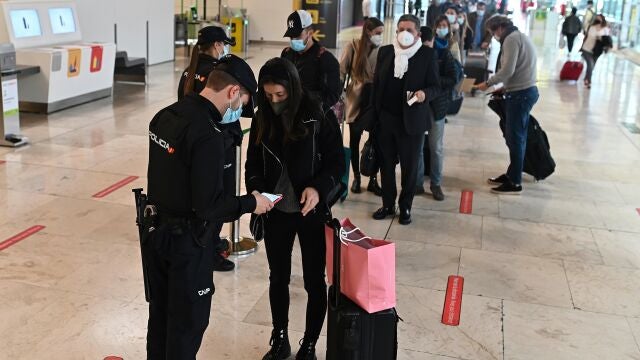 Decenas de pasajeros hacen cola para pasar controles adicionales a los habituales, por la pandemia de coronavirus, en la terminal T4 del aeropuerto de Adolfo Suárez-Barajas