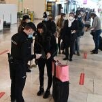 Decenas de pasajeros hacen cola para pasar controles adicionales a los habituales, por la pandemia de coronavirus, en la terminal T4 del aeropuerto de Adolfo Suárez-Barajas