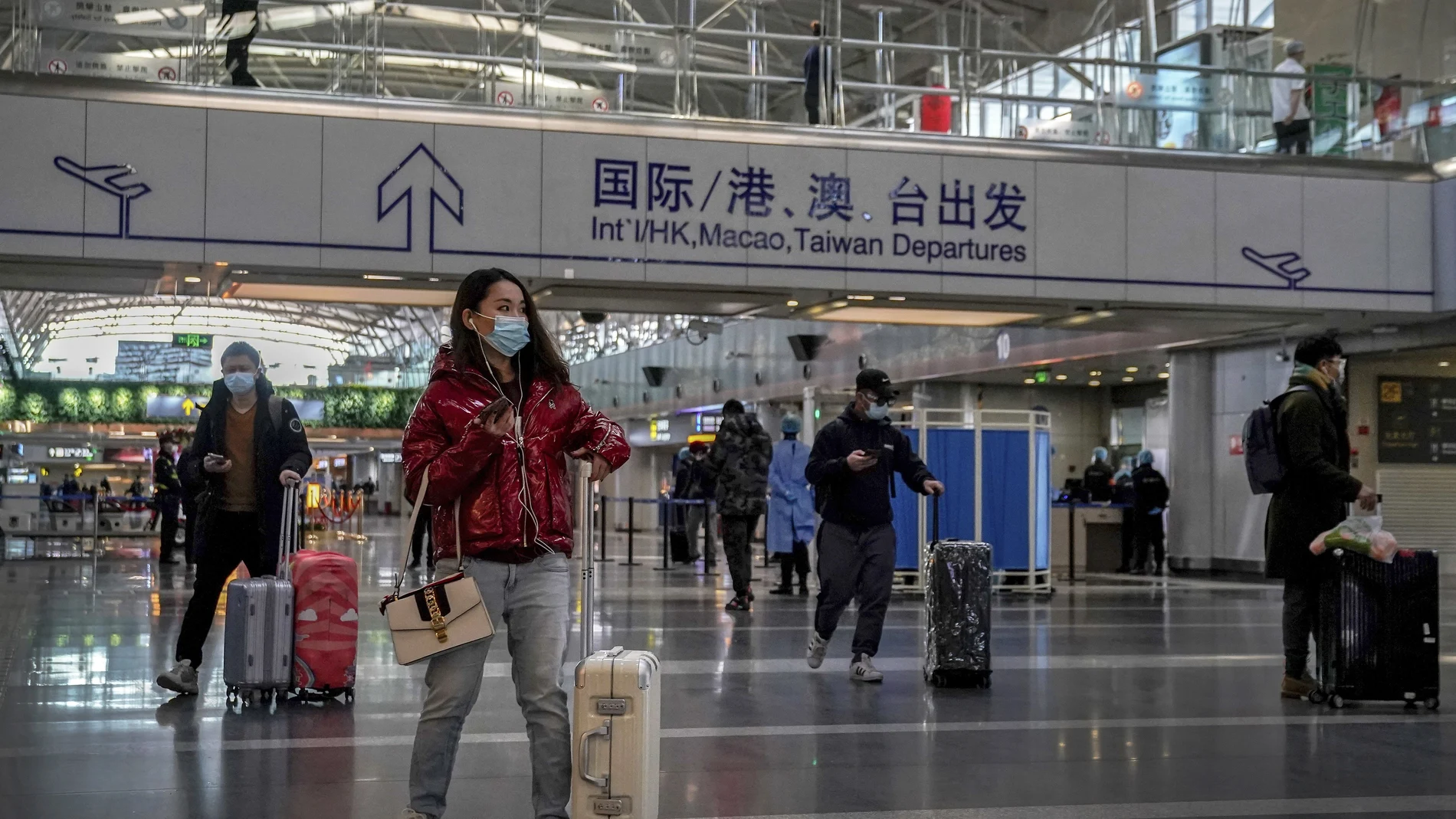 Pasajeros con mascarilla en el aeropuerto de Pekín, mucho más vacío que en otros años