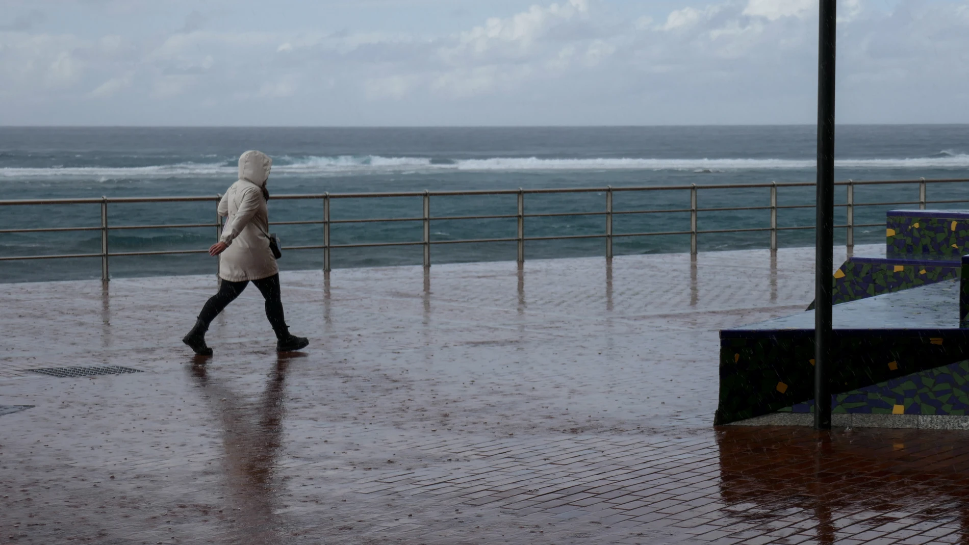 Un hombre camina bajo la lluvia (AEMET).