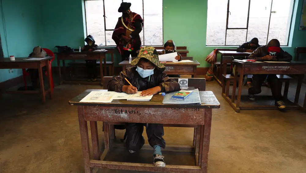 An Aymara Indigenous parent watches over students during the first week back to in-person classes with pupils wearing new protective uniforms amid the COVID-19 pandemic near Jesus de Machaca, Bolivia, Thursday, Feb. 4, 2021. (AP Photo/Juan Karita)