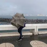  Una persona intenta avanzar ante el fuerte viento y la lluvia
