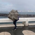  Una persona intenta avanzar ante el fuerte viento y la lluvia