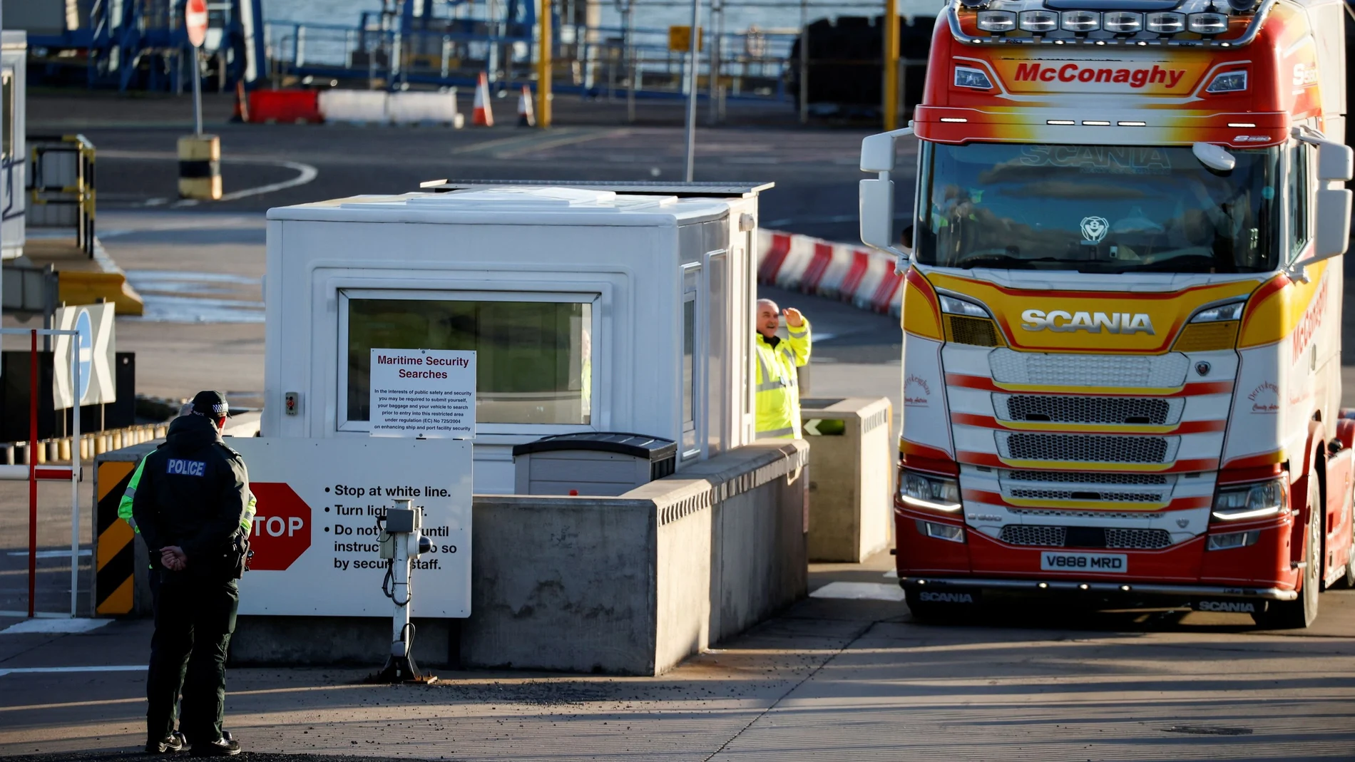 Agentes de policía junto a la seguridad del puerto mientras un camión entra en la entrada del Puerto de Larne, Irlanda del Norte