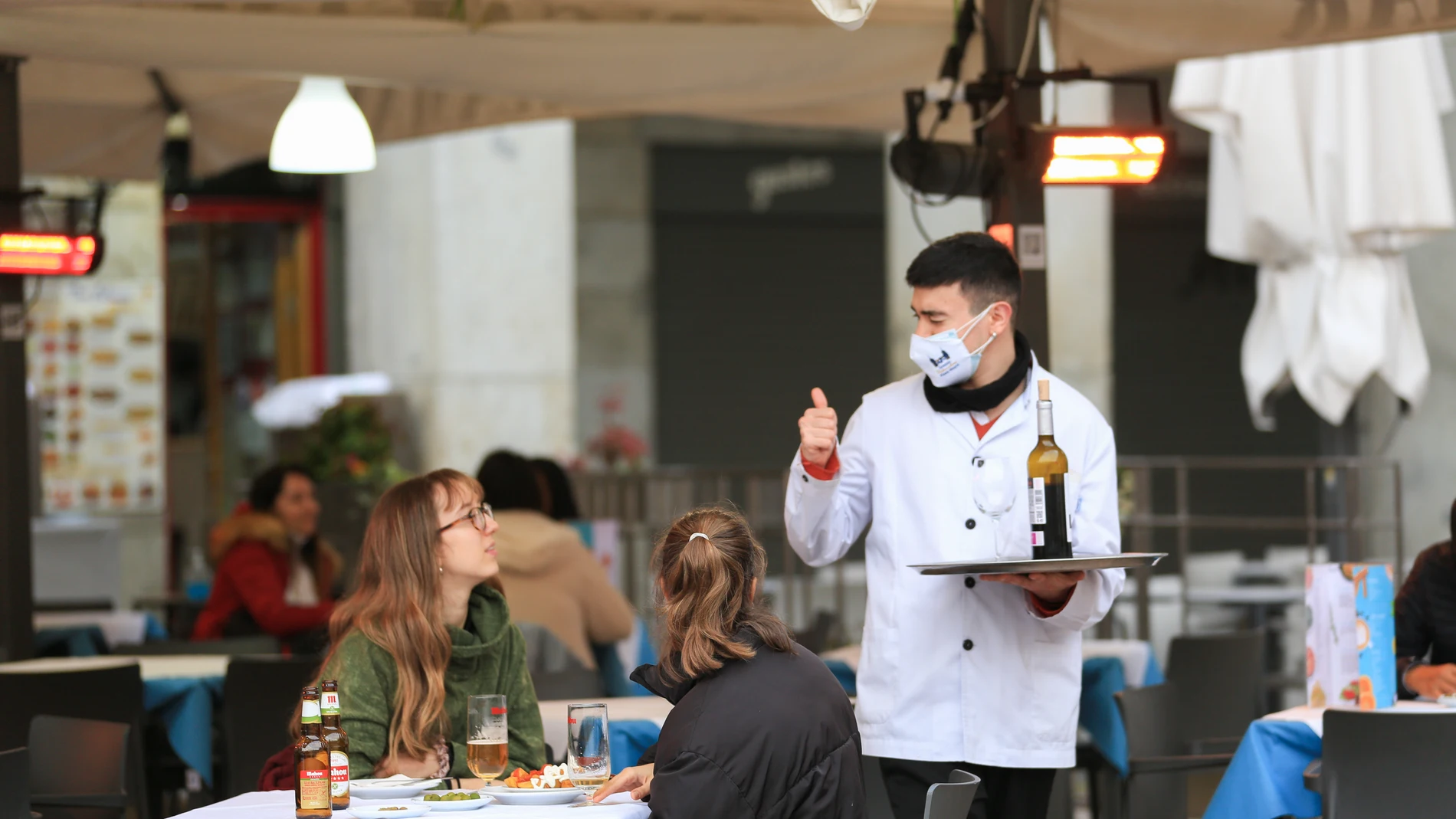 Un camarero atiende a dos clientas en la terraza de un bar en el centro de Madrid