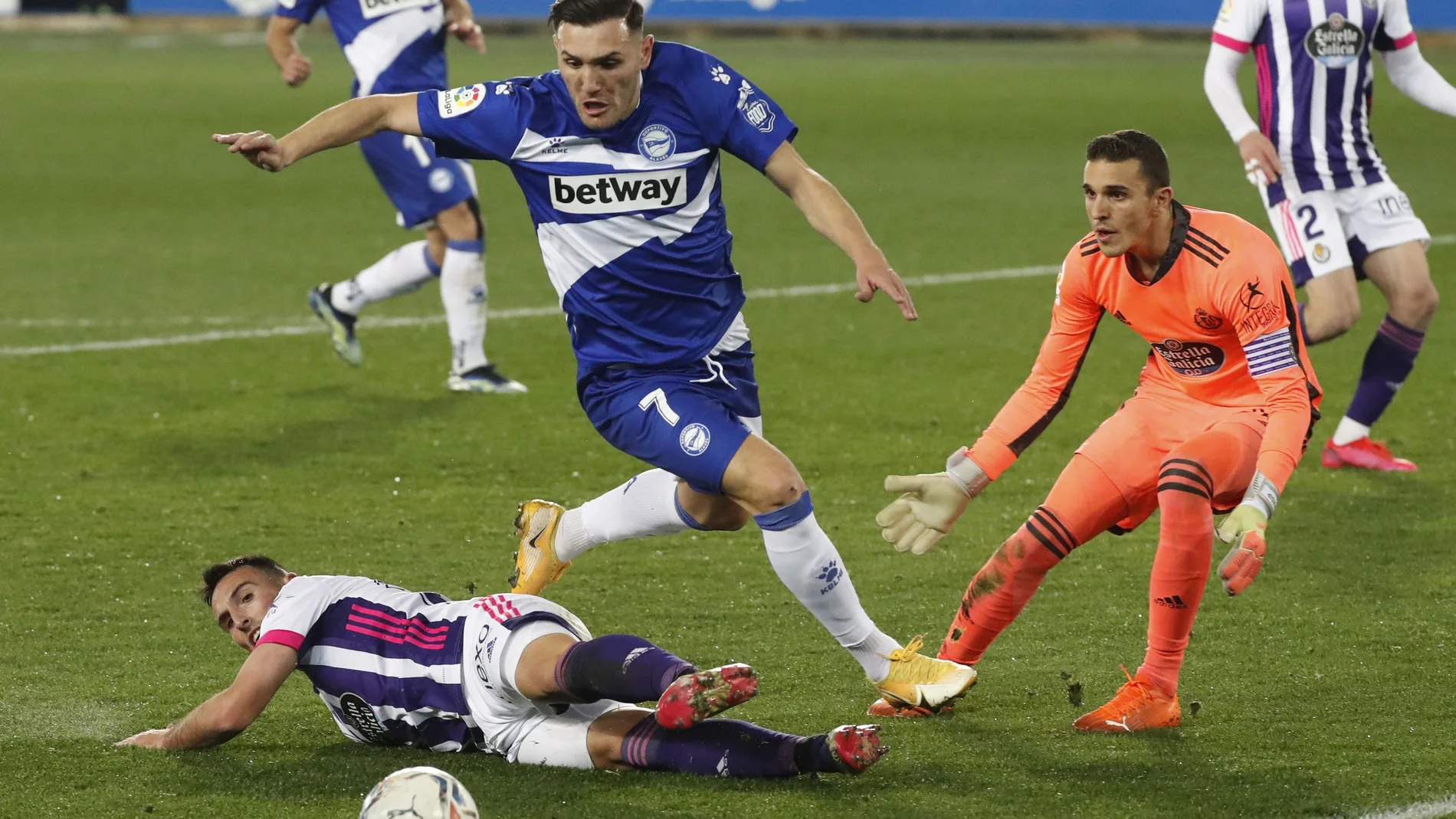 El delantero del Deportivo Alavés Lucas Pérez (c) lucha con Fede (i) y con el portero Jordi Massip, ambos del Real Valladolid, en el partido correspondiente a la jornada 22 de LaLiga Santander de fútbol que se disputa este viernes en el campo de Mendizorrotza, en Vitoria. EFE/David Aguilar