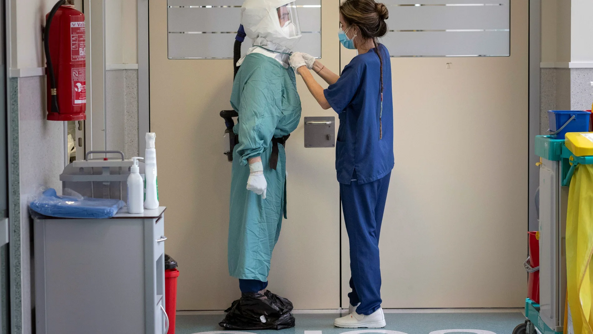 Una enfermera ajusta el Equipo de Protección Personal (EPI) a un enfermero antes de entrar a un box de la Unidad de Cuidados Intensivos (UCI) del Hospital Santa Lucia de Cartagena