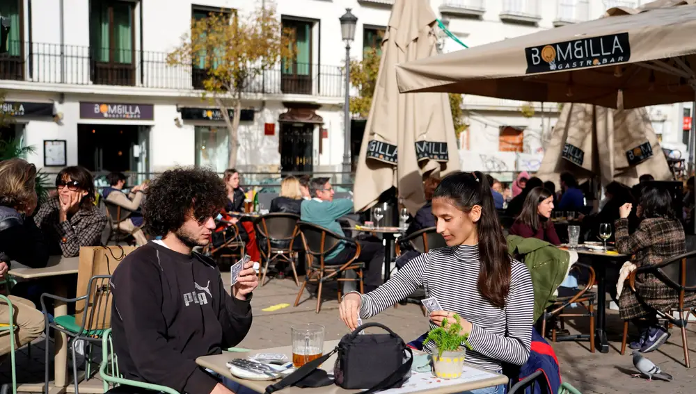Los franceses Theo Perucci y su hermana Luna juegan a las cartas en una terraza en Madrid este fin de semana