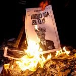 Varias personas participan en la quema popular de fotos del rey durante el acto organizado por la ANC en la víspera de la visita de Felipe VI a Barcelona.