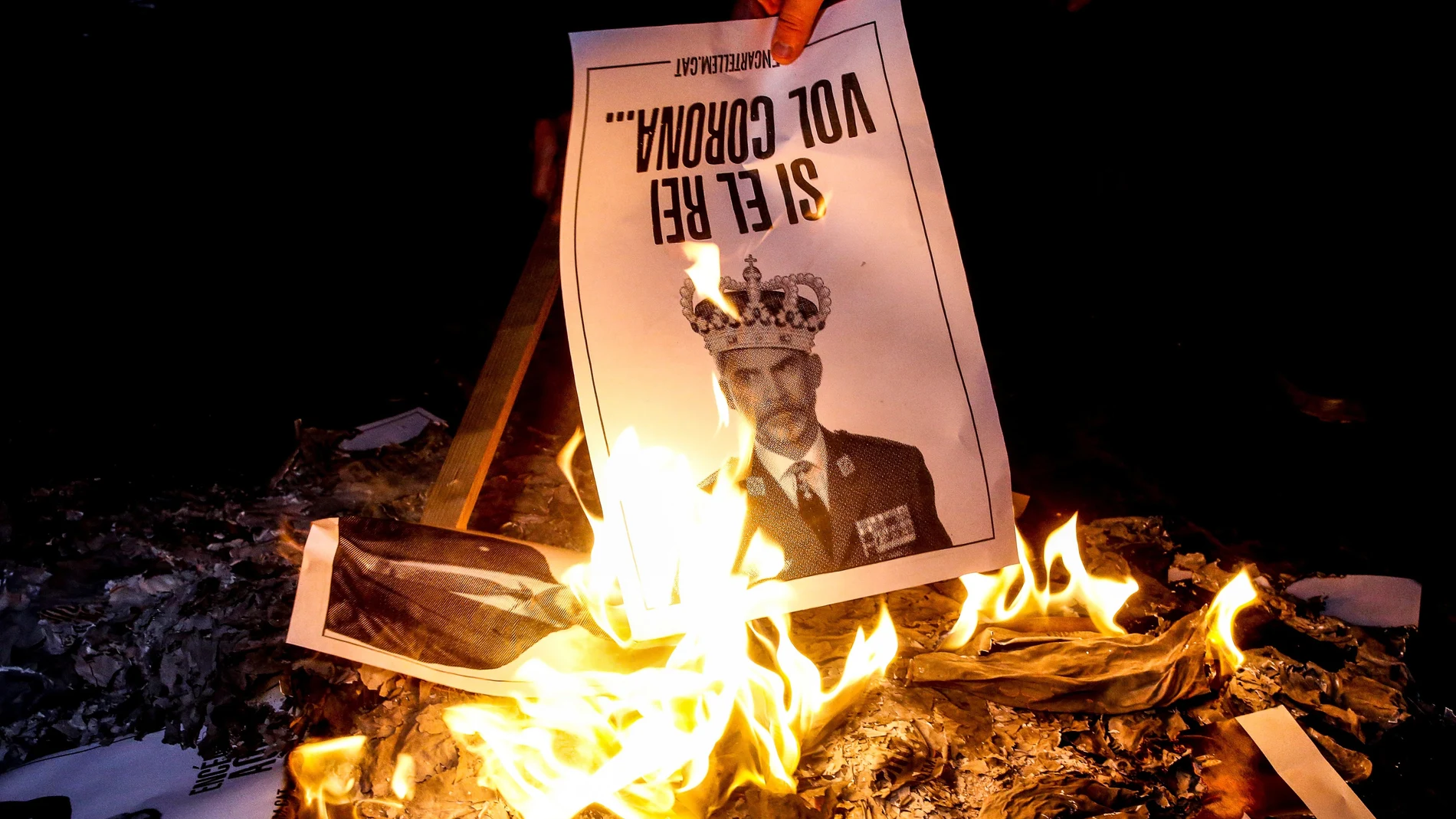 Varias personas participan en la quema popular de fotos del rey durante el acto organizado por la ANC en la víspera de la visita de Felipe VI a Barcelona.