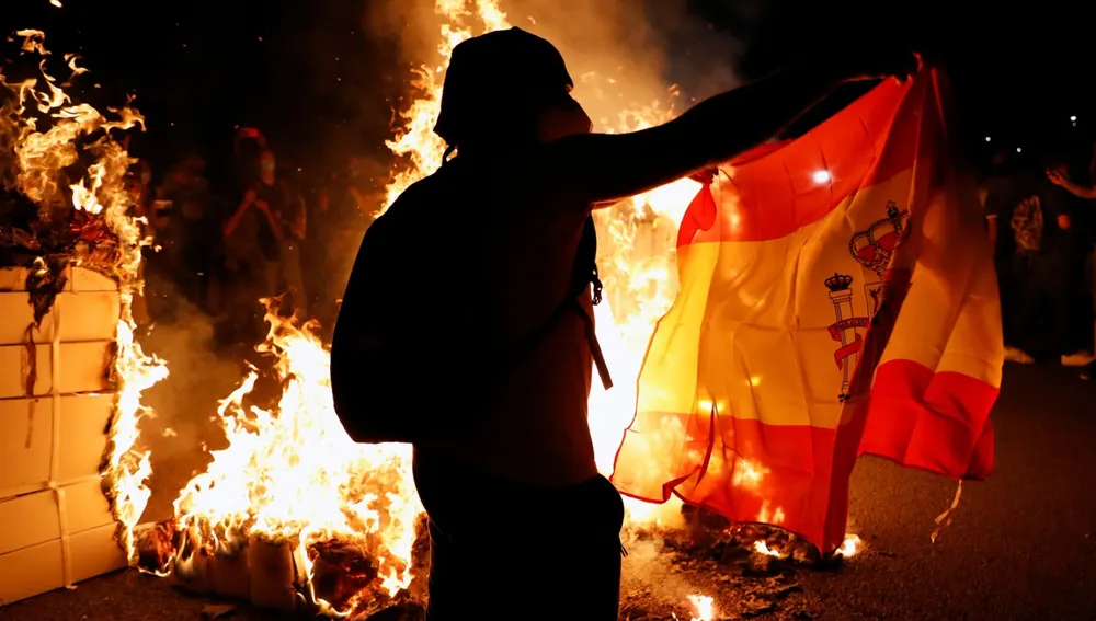 Un manifestante independentista con una bandera de España y junto a una hoguera, durante las manifestaciones de la última Diada