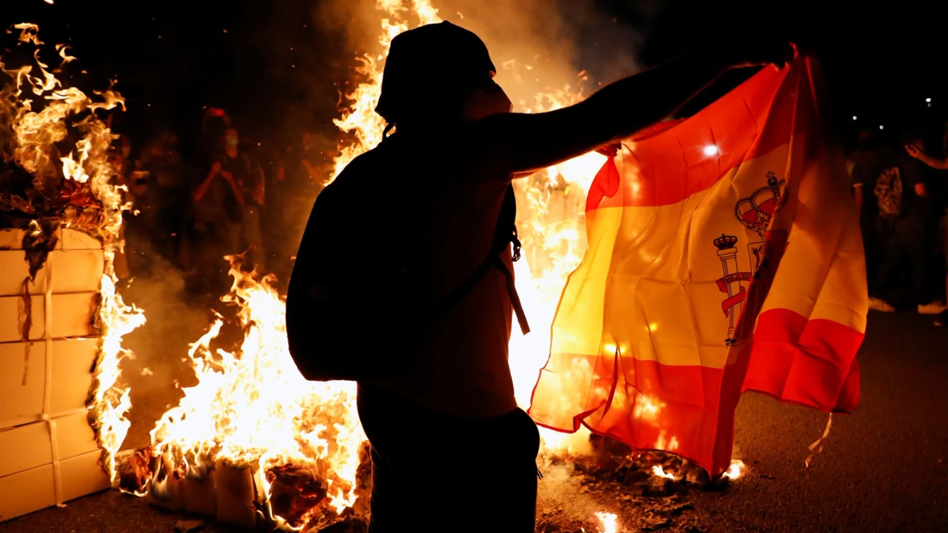 Un manifestante independentista con una bandera de España y junto a una hoguera, durante las manifestaciones de la última Diada