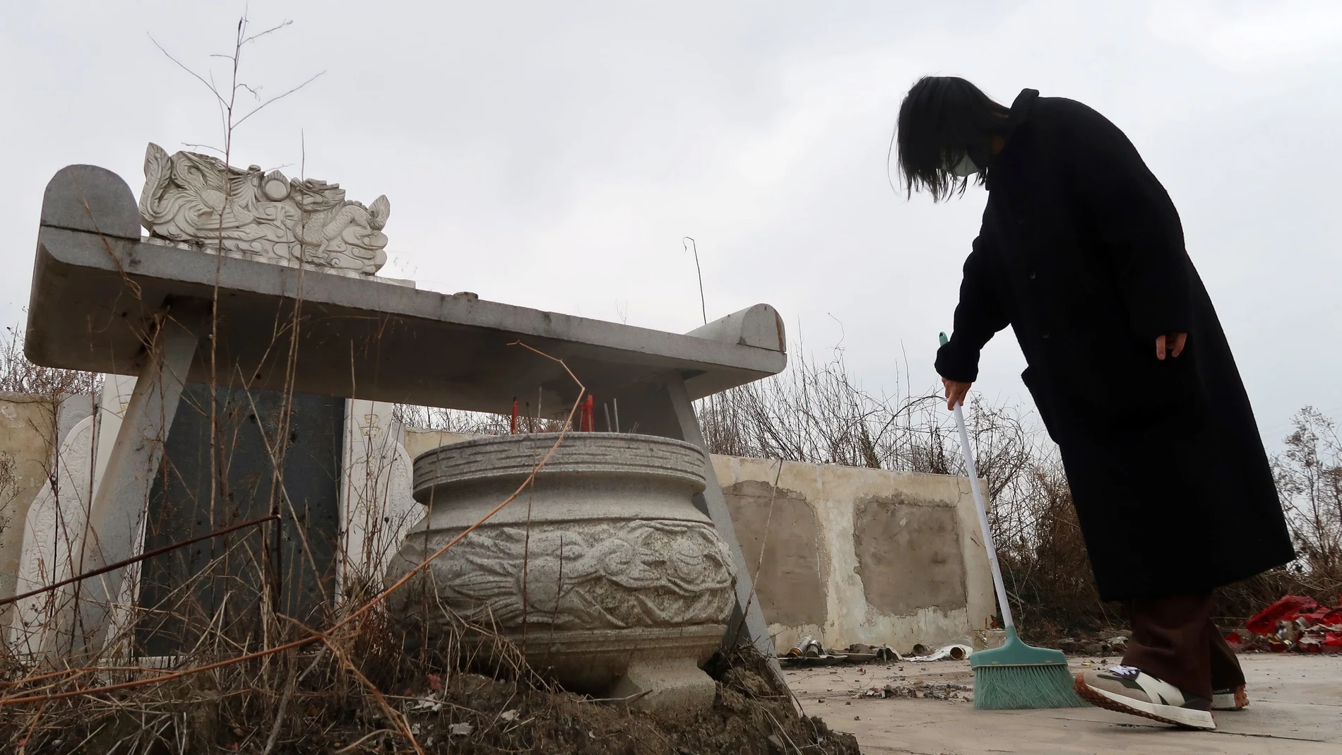 Deng Wei barre las tumbas de su abuela y su padre, fallecidos por coronavirus, en Wuhan (China)