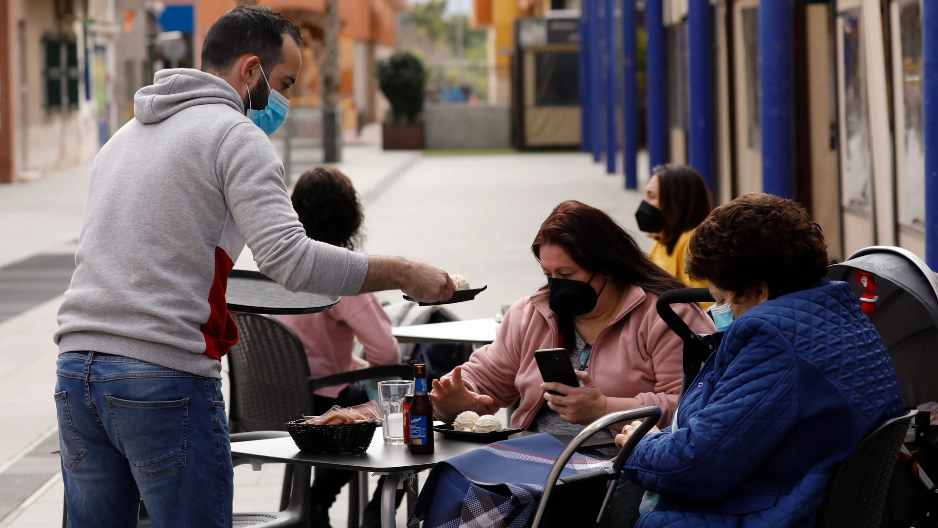 Un camarero atiende a dos clientas en la terraza de un bar, en Alcantarilla, Murcia (España), a 10 de febrero de 2021