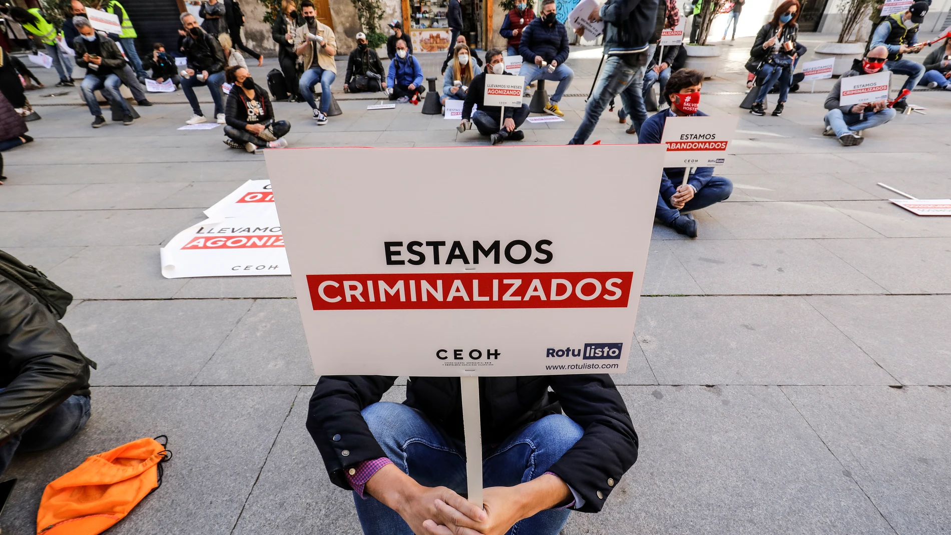 Una persona sostiene una pancarta donde se lee "Estamos criminalizados" durante una manifestación de hosteleros valencianos frente a las puertas del Palau de la Generalitat