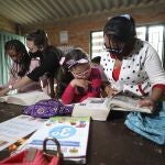 Ana Milena Liberato, right, reads a book with her daughter Wendy Valeria, as they do her biology homework at Los Soches Rural Community Library in Los Soches, a small rural village on the outskirts of Bogota, Colombia, Wednesday, Feb. 10, 2021. Every month Liberato must allocate 50,000 pesos (approximately 15 dollars) to buy internet packages, although in the middle of the new coronavirus pandemic she lost her job. (AP Photo/Fernando Vergara)