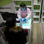 Una farmacéutica prepara un test de antígenos para realizárselo a una mujer en la Farmacia
