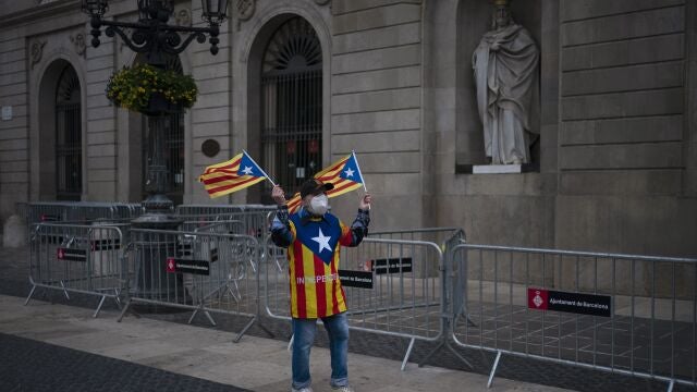 Un votante independentista forrado de esteladas frente a la fachada del Ayuntamiento de Barcelona