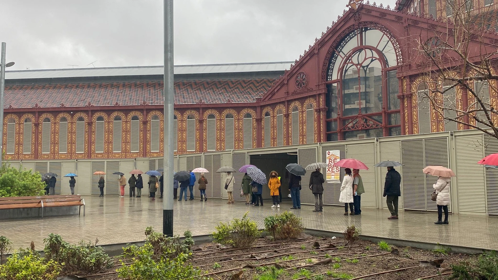 Cola de ciudadanos guardando distancia de seguridad por el coronavirus esperando a votar en el Mercado Sant Antoni de Barcelona en las elecciones catalanas