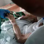 Un sanitario atiende a un anciano muy enfermo en una residencia de Madrid