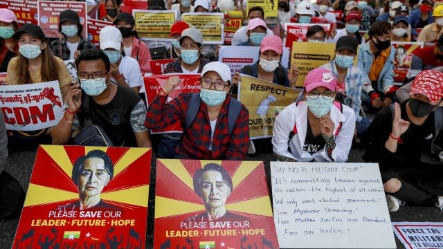 Manifestantes exhiben pancartas con fotografías de Aung San Suu Kyi y un cartel del "Movimiento de desobediencia civil" para protestar contra el golpe militar en Yangon